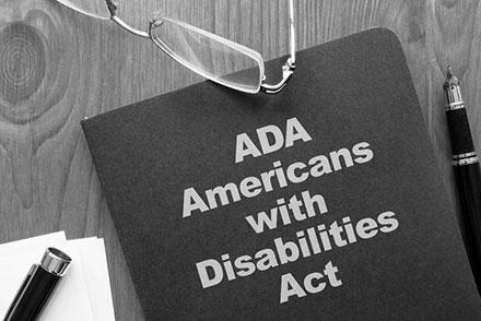 Book titled ADA Americans with Disabilities Act rests on a wooden surface