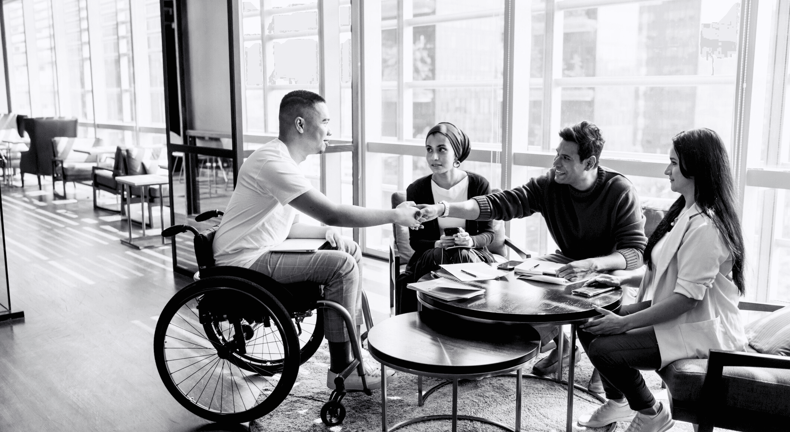 A man in a wheelchair shaking hands with other nonprofit professionals.