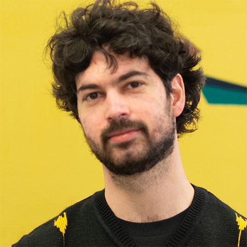 Headshot of Ezra Benus, Disabilities Futures manager, United States Artists, in a black and yellow sweater.