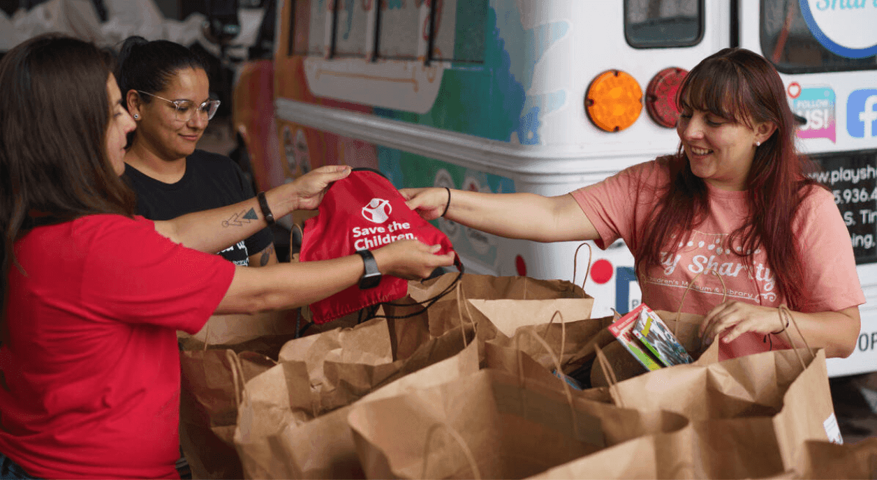 Volunteers at Save the Children passing out shirts.