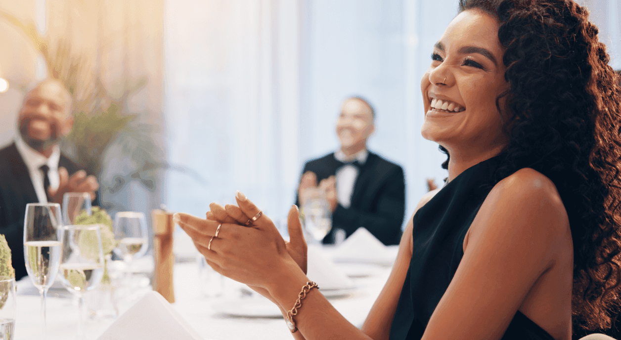 Woman applauding at a fundraising gala table.