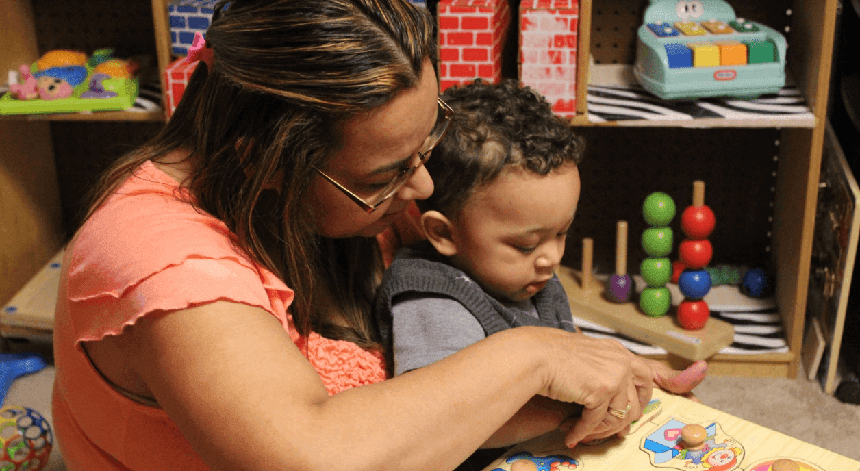 An early childhood educator reading to a toddler.