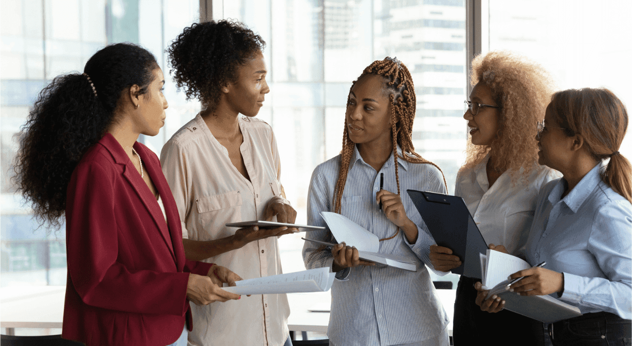 A group of Black women nonprofit leaders talking in an office.