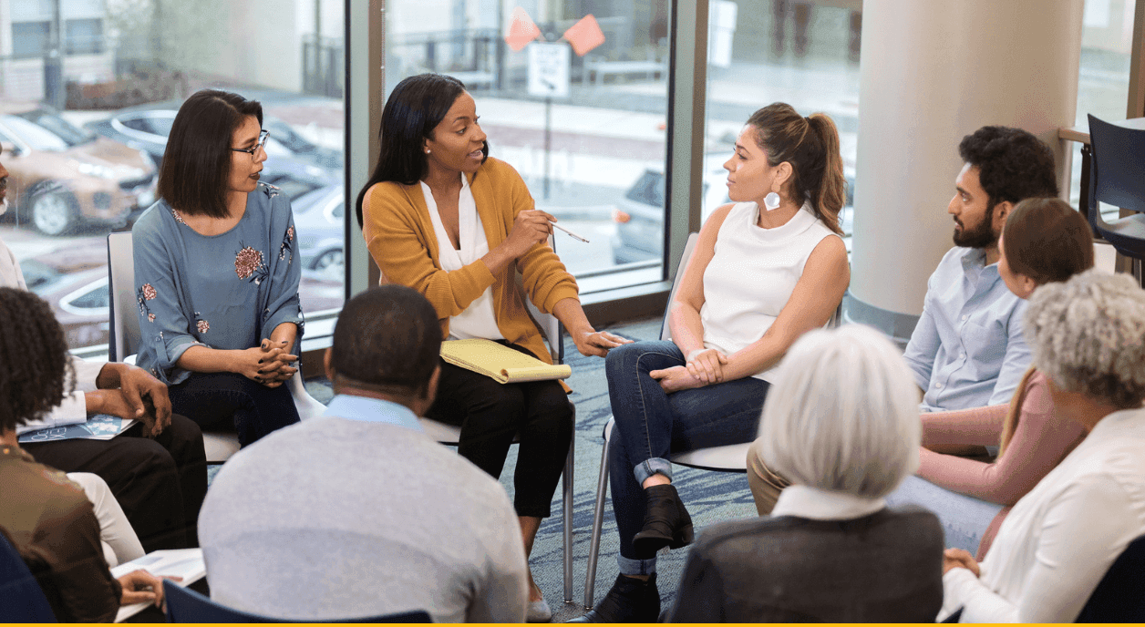 A group of people sitting in a ciricle talking.