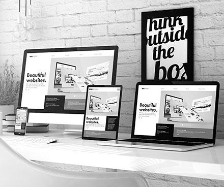 A cell phone, computer monitor, tablet, and laptop displaying the same website.