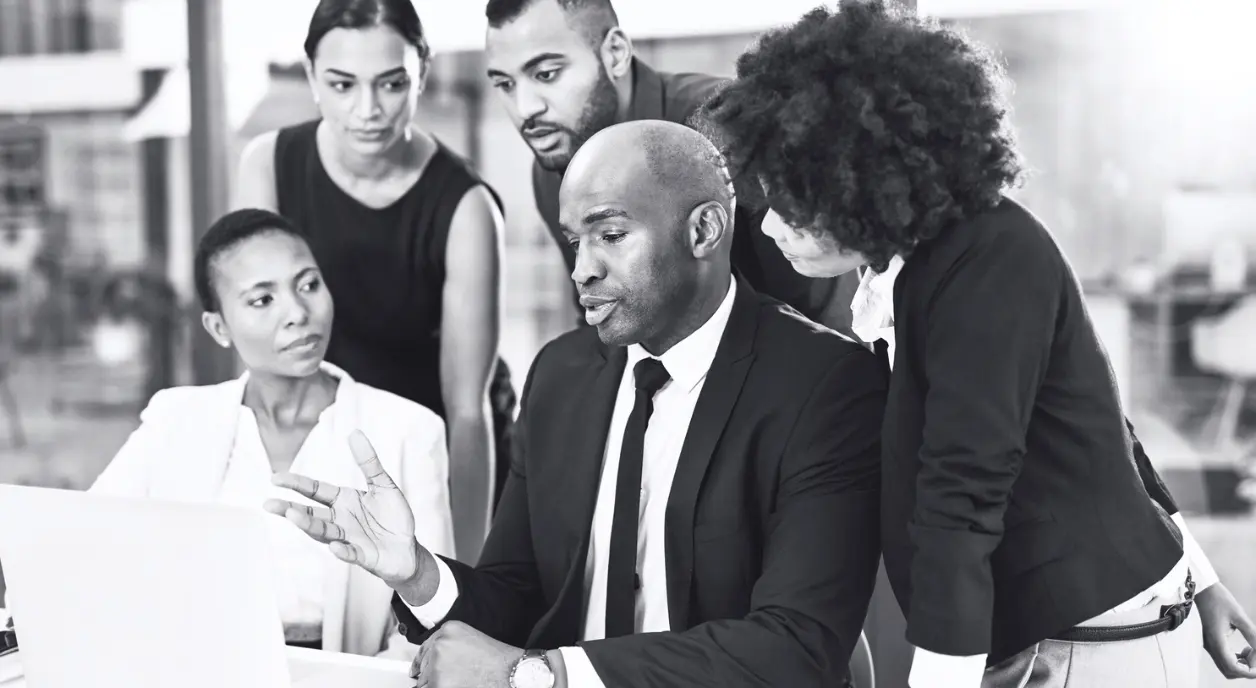 A group of Black business people having a discussion around a laptop.