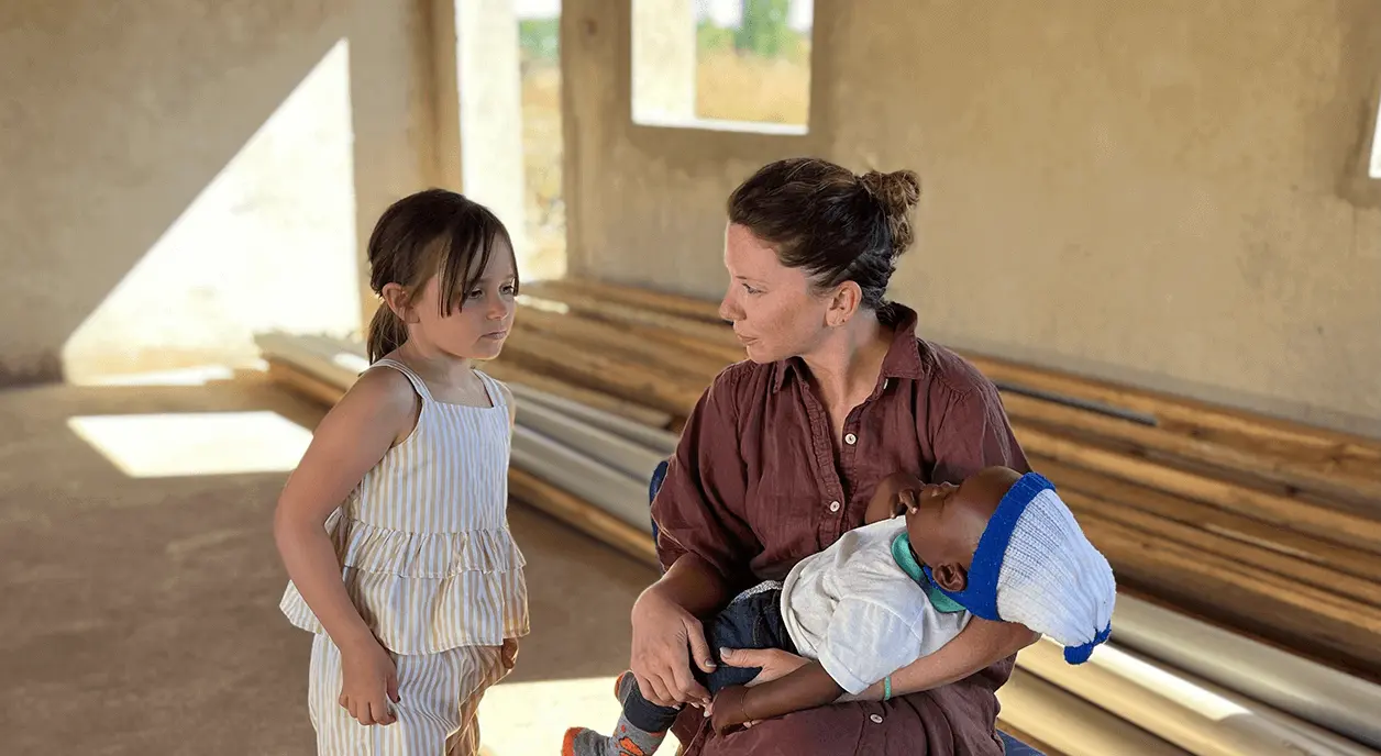 A woman and a young girl taking care of a baby.