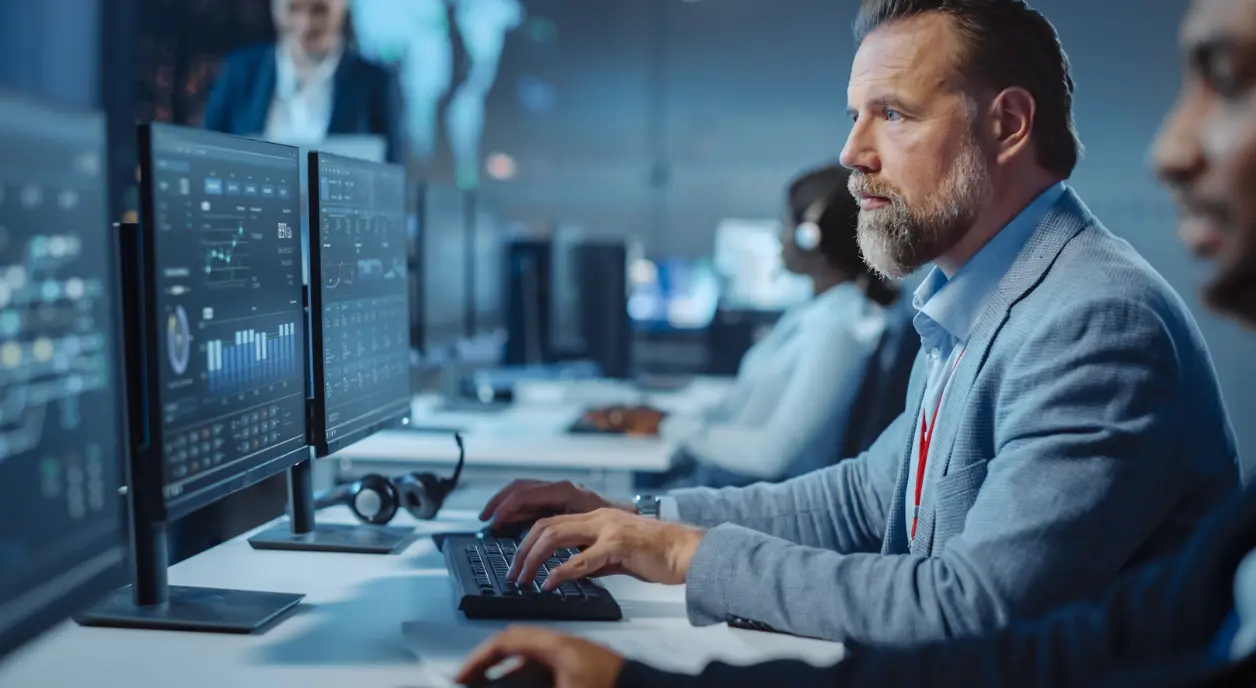 A row of workers looking at data on computer screens.
