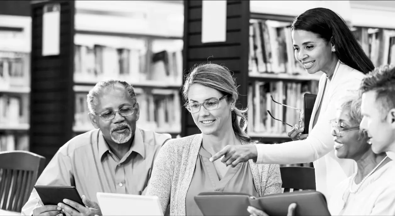 Diverse library patrons at a table looking at tablets. kali9/Getty Images
