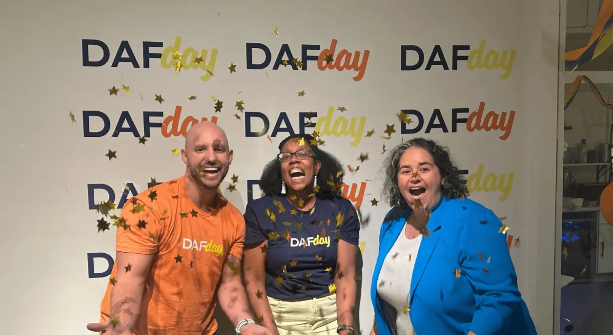 Shayla Titley of the Public Theater between Mitch Stein and Briel Steinberg of Chariot in front of "DAF Day" banner.