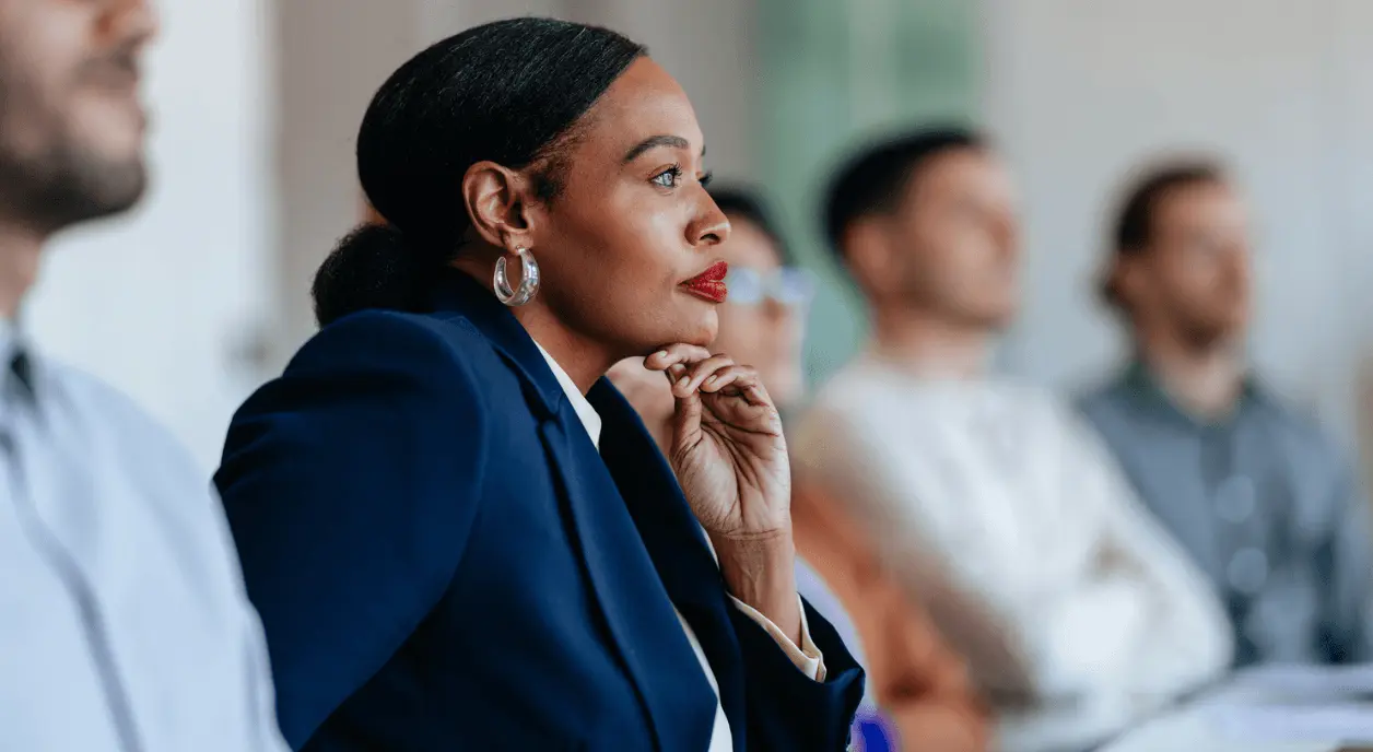 A Black woman thinking at a meeting.