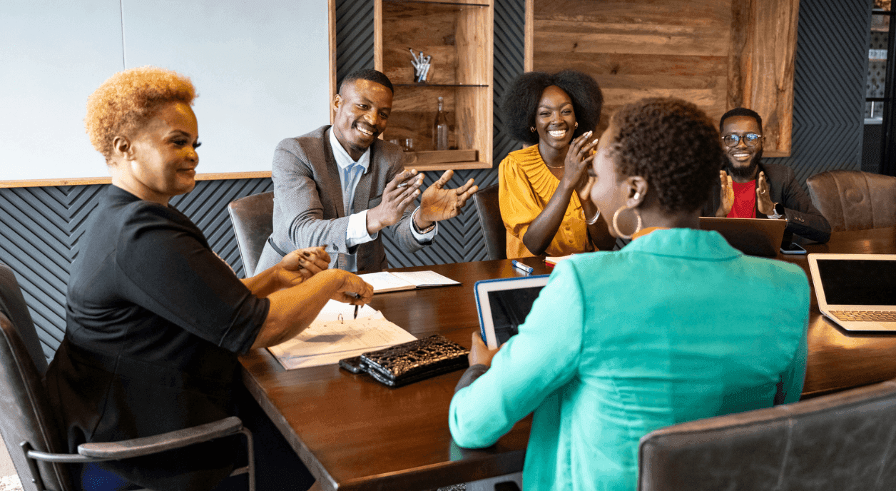 A group of Black nonprofit leaders around a table, some clapping.