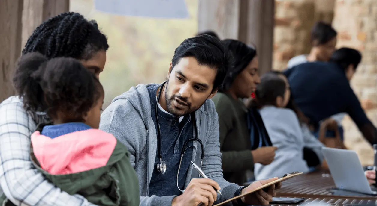 A volunteer doctor talks to a girl and her mother.