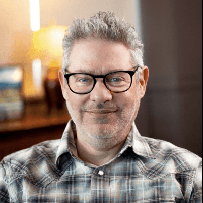Headshot of Sam Caplan, Vice President of Social Impact at Submittable, in glasses and a plaid shirt.